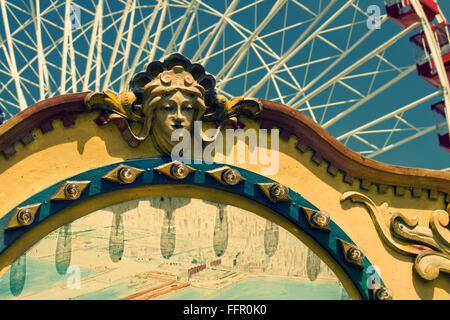 Schnitzen von Frauenkopf auf altes Karussell mit Riesenrad im Hintergrund Stockfoto