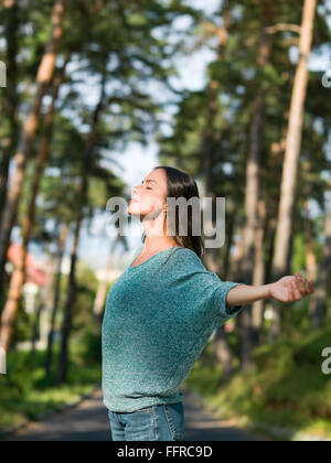 schöne junge Frau, die genießen des warmen Wetter in einer Gasse mit grünen Bäumen Stockfoto