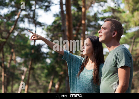 schöne junge Frau zeigt etwas, was sie im Wald sah, genießen das schöne Wetter mit ihrem Freund Stockfoto