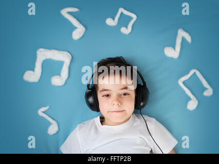 kleiner Junge auf blaue Decke Hintergrund mit Kopfhörer Stockfoto