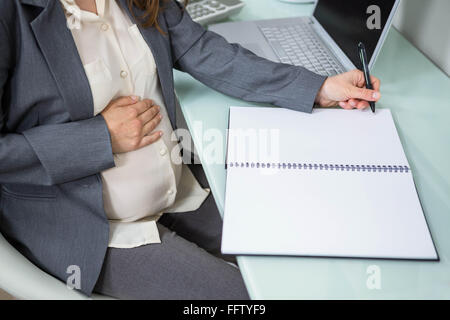 Schwanger Geschäftsfrau im Ordner schreiben Stockfoto