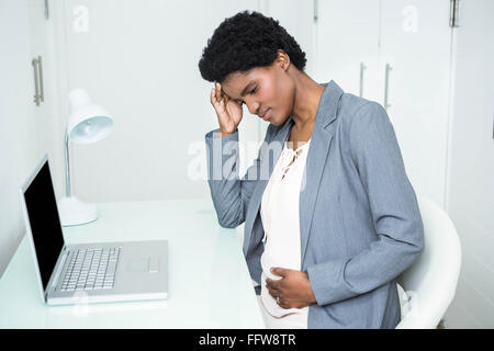 Schwanger Geschäftsfrau, die ihren Kopf und Bauch zu berühren Stockfoto