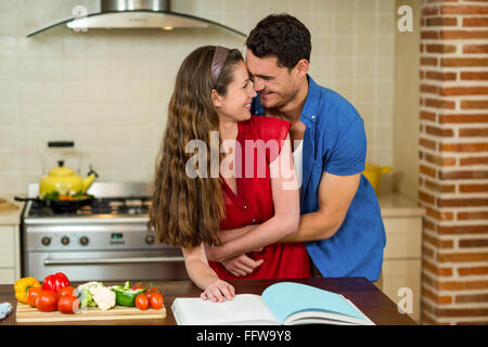 Paar, umarmen, während der Überprüfung des Rezeptbuch Stockfoto