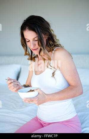 lächelnde Frau, die eine Schüssel Müsli Essen Stockfoto