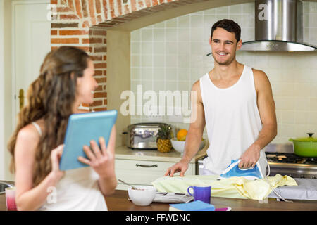 Mann im Gespräch mit Frau während ein Hemd Bügeln Stockfoto