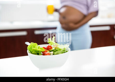 Schwangere Frau in der Küche mit Salat auf Tisch Stockfoto