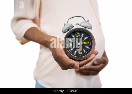 Schwangere Frau mit Wecker Stockfoto