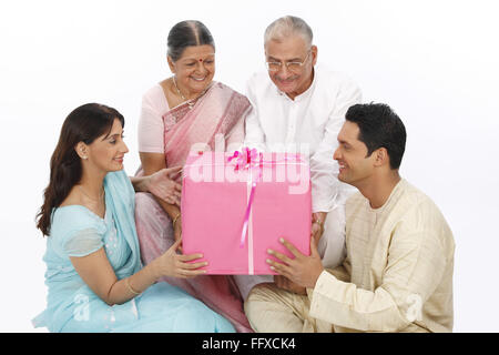 Junge Frau und Mann sitzen halten Geschenkbox und verleihen alten Eltern Herr #703 P, 703Q, 703R, 703S Stockfoto