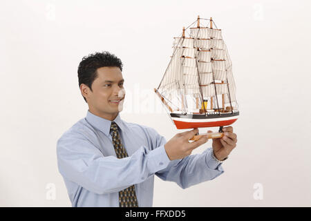 Geschäftsmann hält Miniatur Schiff in beiden Händen Herr #703T Stockfoto