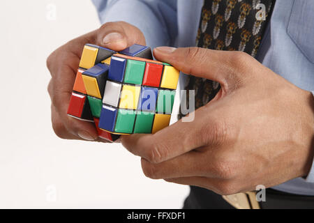 Geschäftsmann Hand Rubik-Würfel in beiden Händen halten und versuchen zu lösen Rätsel Model Release # 703T Stockfoto