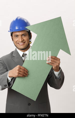 Geschäftsmann mit blauen Helm mit großen Größe, die Farbe grün Pappe Pfeil in beide Herr #703T Hände holding Stockfoto