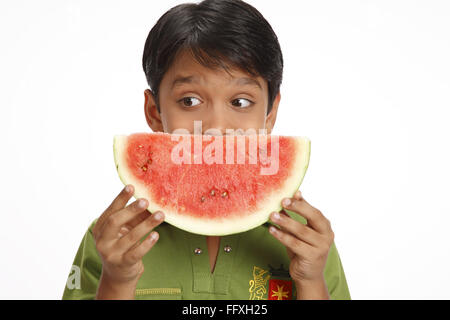 Zehn Jahre alter Junge hält eine halbe Runde Wassermelone Scheibe mit beiden Händen in der Nähe seiner Mündung Herr #703V Stockfoto