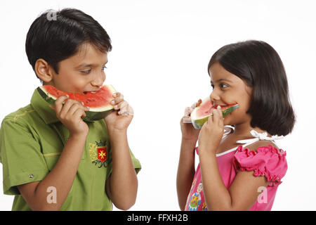 Zehn und acht Jahre alten Jungen und Mädchen, die halten Wasser eine halbe Runde Melonenscheiben und Einnahme Biss Herr #703U 703V Stockfoto