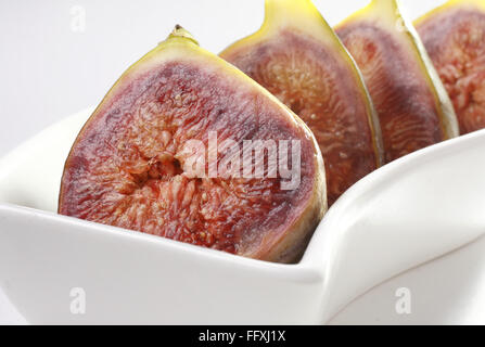 Obst, Feigen Ficus Carica Anjir zwei im Schnitt vier halbieren in s Form weiße Platte auf weißem Hintergrund gehalten Stockfoto