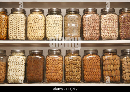 Trockene Früchte Cashewnuss Rosinen Pistazien Mandelnuss getrocknete Aprikose in verschiedenen Gläsern auf Regalen im Geschäft gehalten Stockfoto