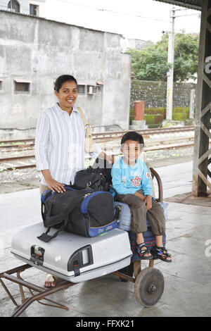 Mutter stand und Sohn sitzen auf Gepäck gehalten auf Wagen Herr #468 Stockfoto