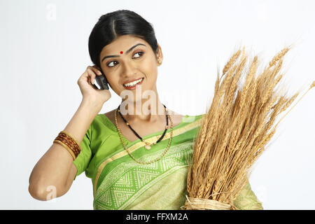 Reichen indischen Bauern Frau hält geerntet, goldener Weizen ernten und sprechen auf mobile Herr #743B Stockfoto