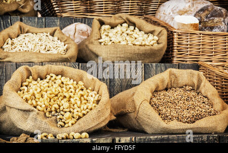 Teigwaren und Gebäck in big-Bags auf Retro-Holzbrett. Essen-Thema. Lebensmittelgeschäft. Stockfoto