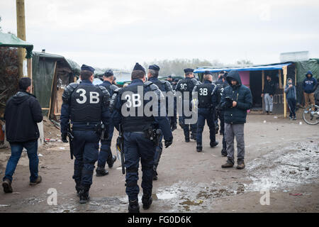 Bewaffnete französische Polizei geht durch das Dschungel-Flüchtlingslager, Calais, Frankreich. Stockfoto