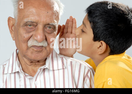 Südasiatische indische Enkel teilen Geheimnis ins Ohr Großvater Herr #152 Stockfoto