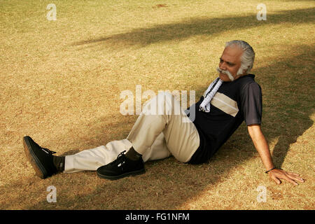 Älterer Herr mit dunklem Blau-T-Shirt über sechzig Jahre alt, Ruhe und Entspannung im Schatten im Park Herr #671 Stockfoto