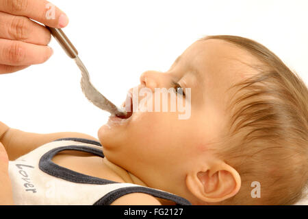 Ein Jahr alten baby boy Lügen füttern mit Löffel - HERR #592 Stockfoto