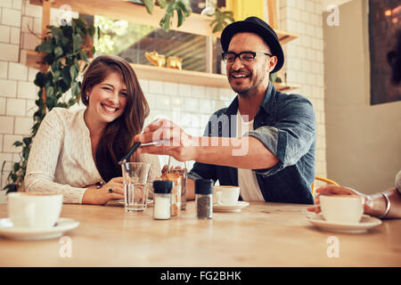 Porträt von glücklicher junger Mann zeigt sein Handy an Freunde sitzen in einem Café. Stockfoto
