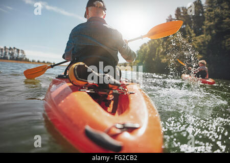 Rückansicht des Menschen paddeln Kajak in See mit Frau im Hintergrund. Paar Kajak in See an einem sonnigen Tag. Stockfoto