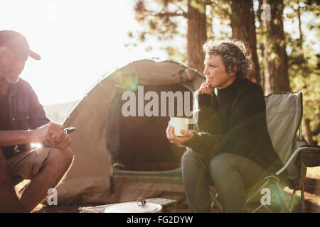 Porträt von entspannt Mitte erwachsenes paar Zelt beim camping in der Nähe am See an einem sonnigen Tag draußen. Frau mit Kaffee tal Stockfoto