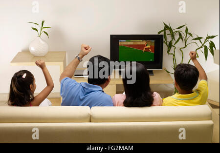 Kinder, deren Eltern jubeln und sich im Fernsehen ein Spiel anschauen, sitzen IM Haus MR#702R,MR#702S,MR#702T,MR#702U Stockfoto