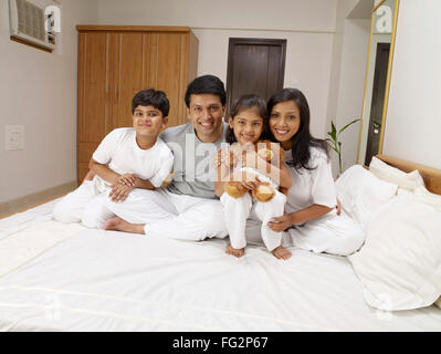 Eltern mit Kinder sitzen auf dem Bett im Schlafzimmer Herr #702R, Herr #702S, #702T Herr, Herr #702U Stockfoto