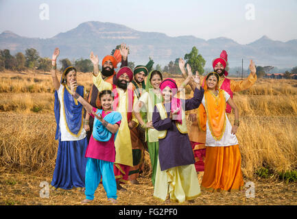 Sikh-Familie mit Tänzerinnen Volkstanz Bhangra in trockenen Rasen Herr #702 X; 702Y; 779A; 702Z; 779C; 779B; 779D; 779E 779F Stockfoto