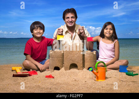 Vater an Hand der Kinder am Sandburg am Meeresstrand Herr #779 H; 779G; 477 Stockfoto