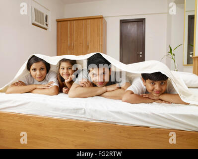 Eltern mit Kindern unter Bett Laken liegend auf dem Bett im Schlafzimmer Herr #702R, Herr #702S, #702T Herr, Herr #702U Stockfoto