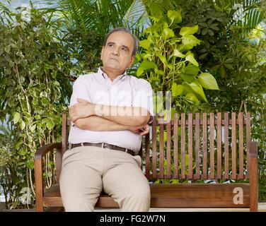Alter Mann in seinem eigenen Denken sitzen auf Holzbank Herr #702T Stockfoto