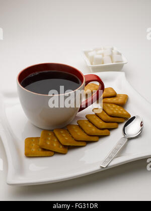 Tasse schwarzer Tee im Teller mit Zucker Würfel und Kekse Indien Stockfoto