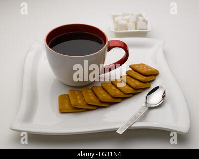 Tasse schwarzer Tee im Teller mit Zucker Würfel und Kekse Indien Stockfoto