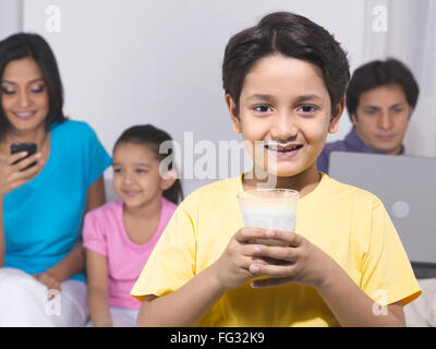 Junge hält ein Glas mit seiner Familie im Hintergrund Herr #779 P; HERR #779Q; HERR #779R; HERR #779S Stockfoto