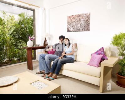 Junger Mann und Frau umarmt auf Sofa Herr #702V, 702U Stockfoto