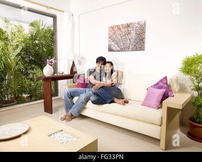 Junger Mann und Frau umarmt auf Sofa Herr #702V, 702U Stockfoto