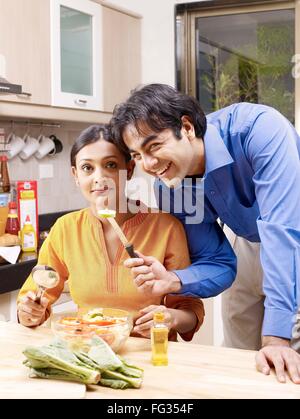 Junger Mann halten Messer mit Scheibe Gurke und Frau mit Löffel Herr #702V Stockfoto