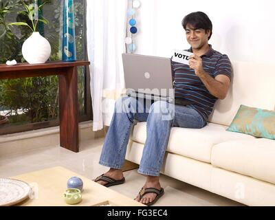 Mann mit Laptop halten weiße Karte gedruckten Stimmen in englischer Sprache Herr #702V Stockfoto