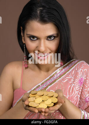 Mädchen in Sari Goldmünzen in den Handflächen Hand hält Stockfoto