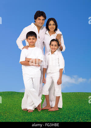 Eltern und Kinder in weißen Kostümen stehen auf dem grünen Rasen Stockfoto