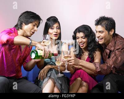 South Asian indischen Mann gießt Champagner in Gläsern von Freunden feiern Partei Herr Stockfoto