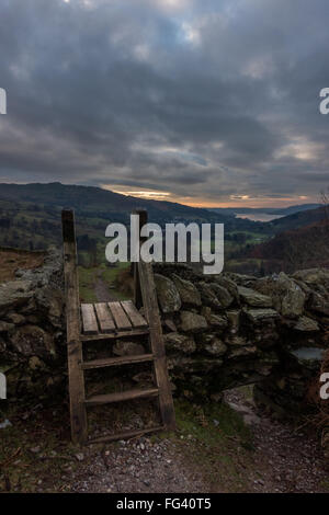 Auf der Suche nach unten über einen hölzernen Stil in Richtung Ambleside und Windermere von Anfang an das Fairfield Hufeisen, Lake District, Großbritannien Stockfoto