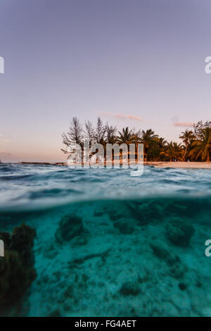 Haus am Strand und blau tropische Gewässern gesehen vom Gewässerrand halb unter und halb über der Wasserlinie Stockfoto