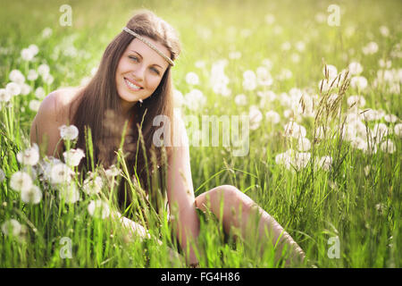 Schöne junge Frau lächelnd auf einer blühenden Wiese. Natur-Harmonie und Gelassenheit Stockfoto