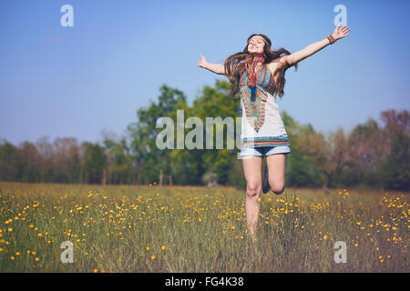 Glücklich und lächelnd Hippie-Frau springt in eine Sommerwiese. Vintage Photo-Effekt Stockfoto