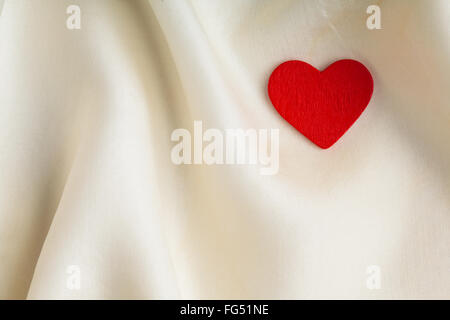 Valentinstag oder Hochzeit. Herz rot aus Holz dekorative auf abstrakte weißen Hintergrund Luxus Tuch Seide oder satin Textil. Stockfoto